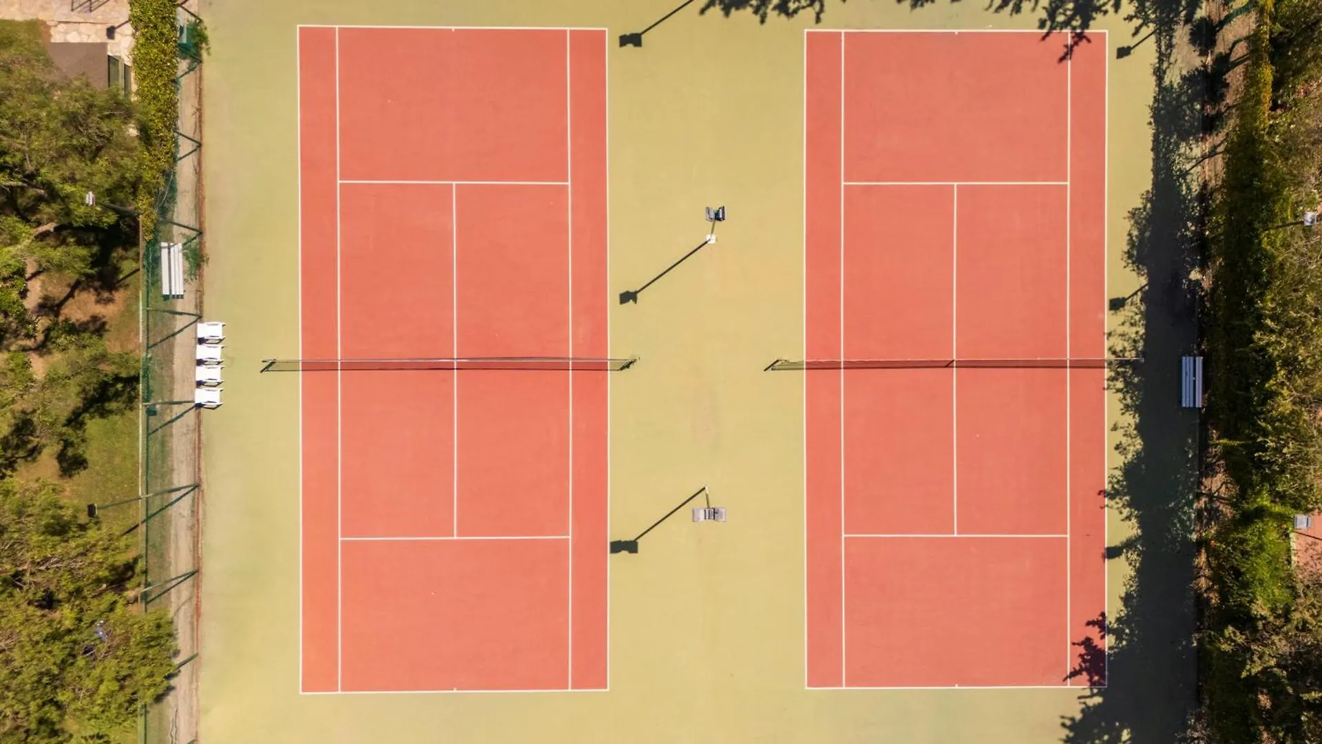 Limak Limra Hotel & Resort Kemer - Kids Concept Exterior photo The photo is an aerial view of a tennis court complex. There are two separate tennis courts, side-by-side, both featuring a red playing surface with white lines marking the boundaries. 

The courts are surrounded by a light green or beige area, likel